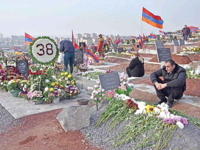 مواطنون أرمن يزورون قبور أقاربهم الذين سقطوا في معارك كاراباخ في يريفان أمس الأول (أ ف ب)