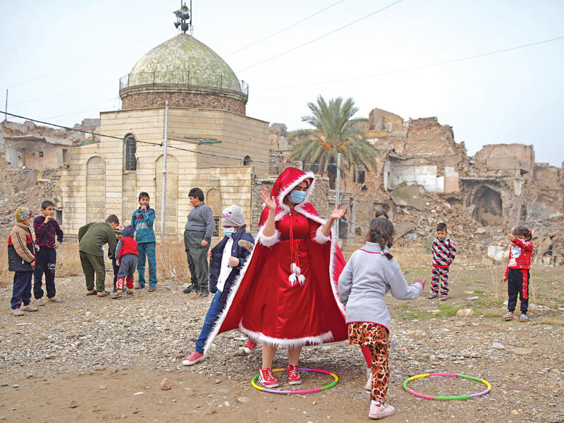 عراقية ترتدي زي «بابا نويل» وتلعب مع أطفال في الموصل القديمة احتفالاً بحلول السنة الميلادية الجديدة