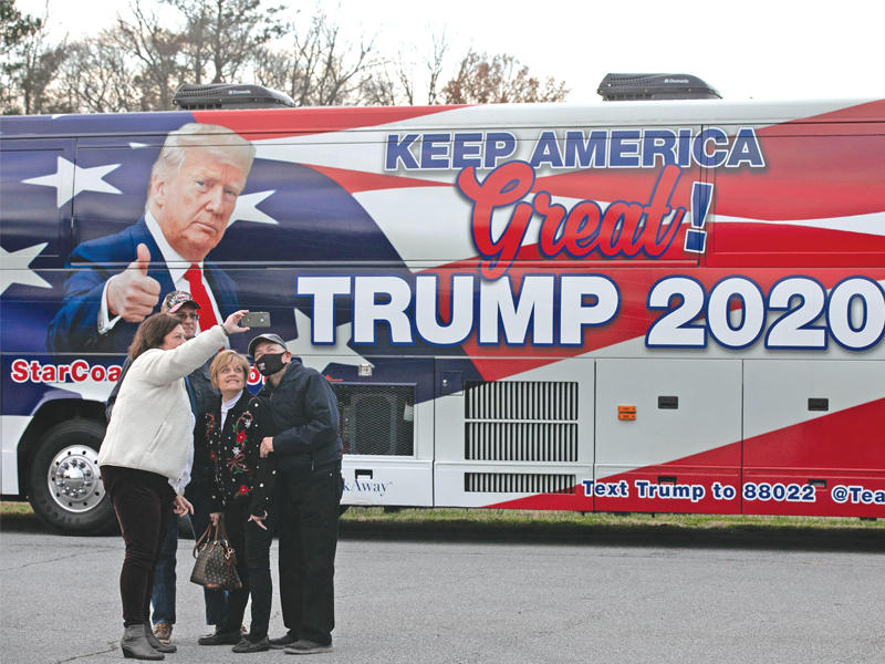 سيلفي لأنصار دونالد ترامب مع حافلة لحملته خلال تجمع جمهوري بجورجيا أمس الأول (أ ف ب)