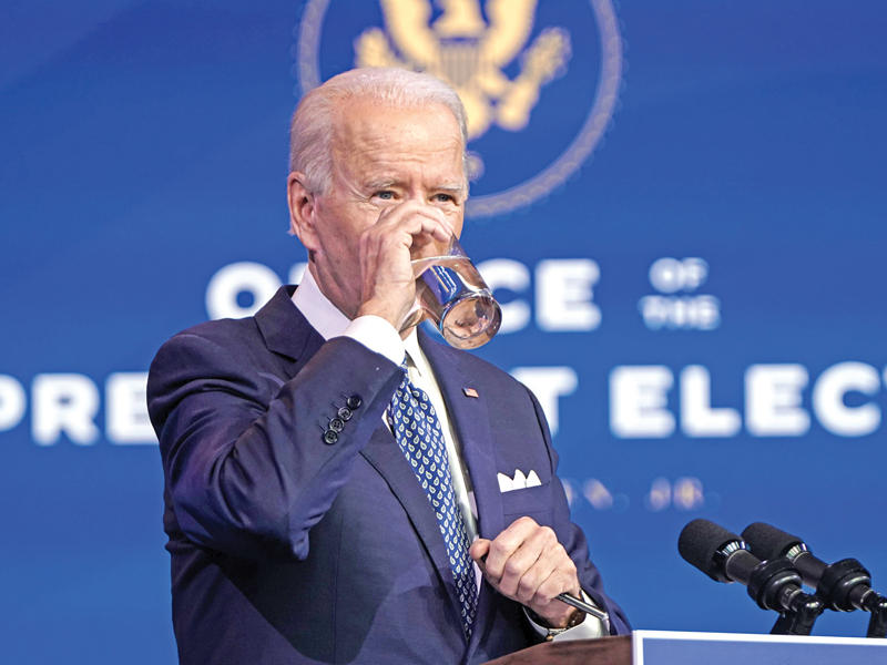 جو بايدن يشرب الماء خلال كلمته في ويلمنغتون أمس الأول (أ ف ب)