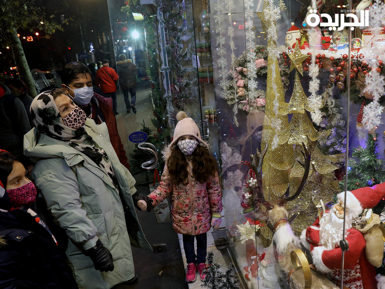 عائلة إيرانية تنظر إلى معروضات متجر لهدايا عيد الميلاد في طهران
