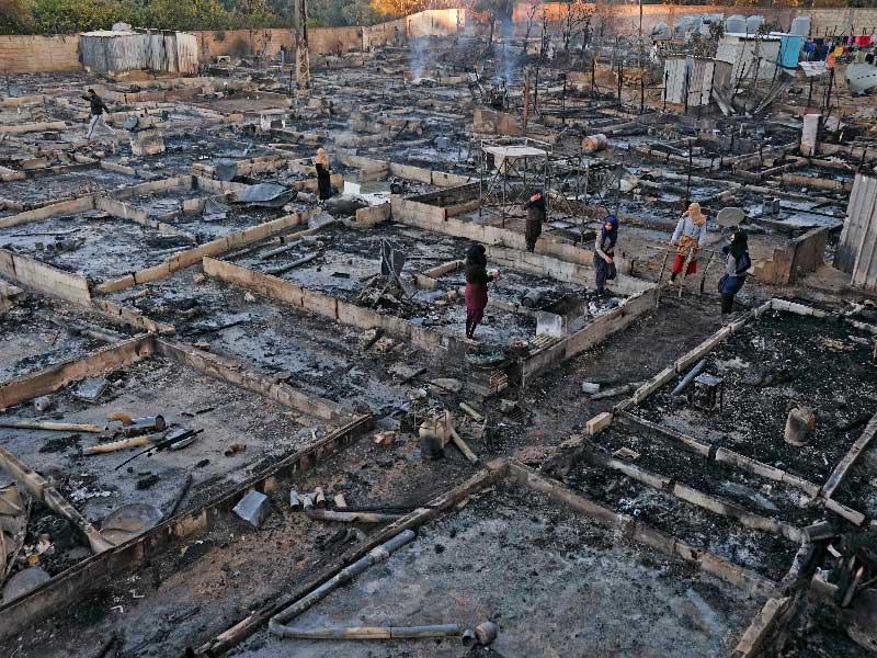 لاجئون سوريون يقفون فوق رماد خيمهم التي التهمها الحريق في شمال لبنان أمس (أ ف ب)