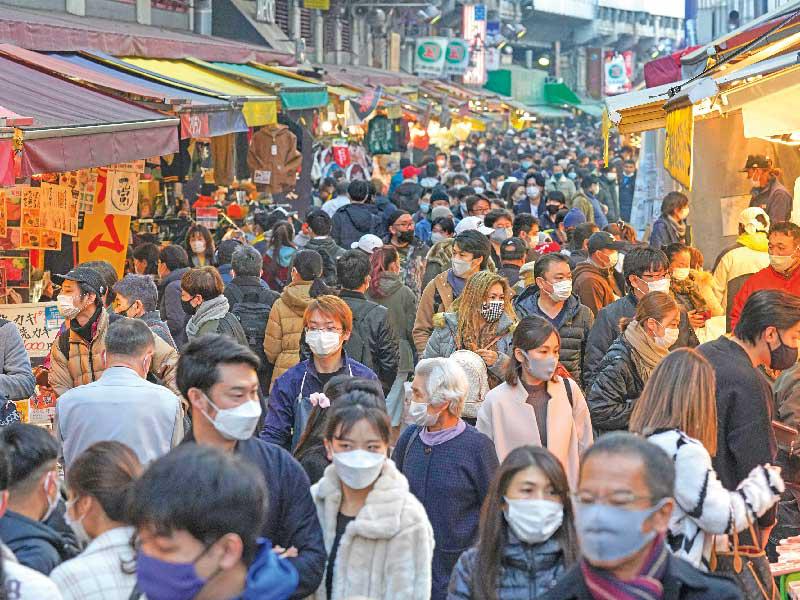 يابانيون يضعون كمامات خلال تسوّقهم استعدادًا للاحتفال بنهاية العام الجديد بشارع أميوكو في طوكيو أمس (اي بي اي)