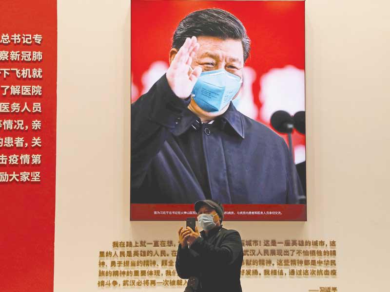 رجل يقف أمام صورة للرئيس الصيني في مدينة ووهان أمس (رويترز)