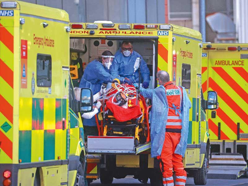 مسعفون ينقلون مصاباً بـ«كورونا» إلى مستشفى لندن الملكي في لندن أمس الأول (رويترز)