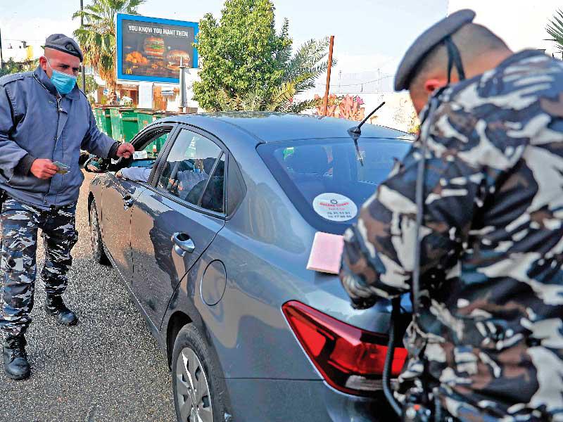 شرطي يحرّر مخالفة بحق مواطن خرق حظر التجوّل المفروض للحدّ من تفشّي «كورونا» في بيروت أمس (ا ف ب)