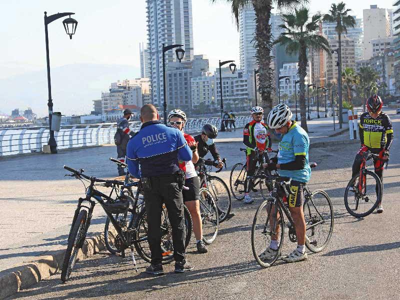 شرطي يخالف ركاب دراجات هوائية خرقوا حظر التجوّل في بيروت أمس (أ ف ب)