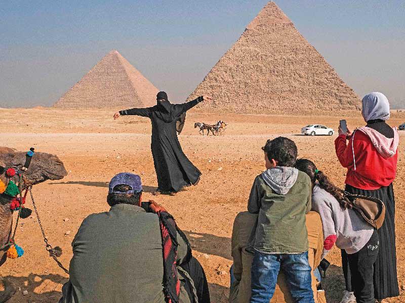امراة تلتقط صورة أمام أهرامات الجيزة (أ ف ب)