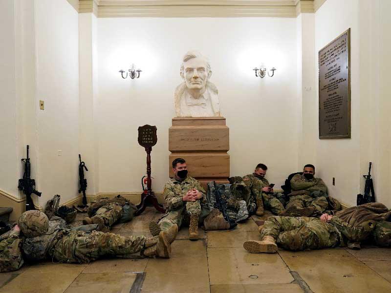 عناصر الحرس الوطني في استراحة داخل إحدى قاعات الكابيتول أمس الأول إلى جانب تمثال رأسي للرئيس أبراهام لنكولن t(رويترز) 