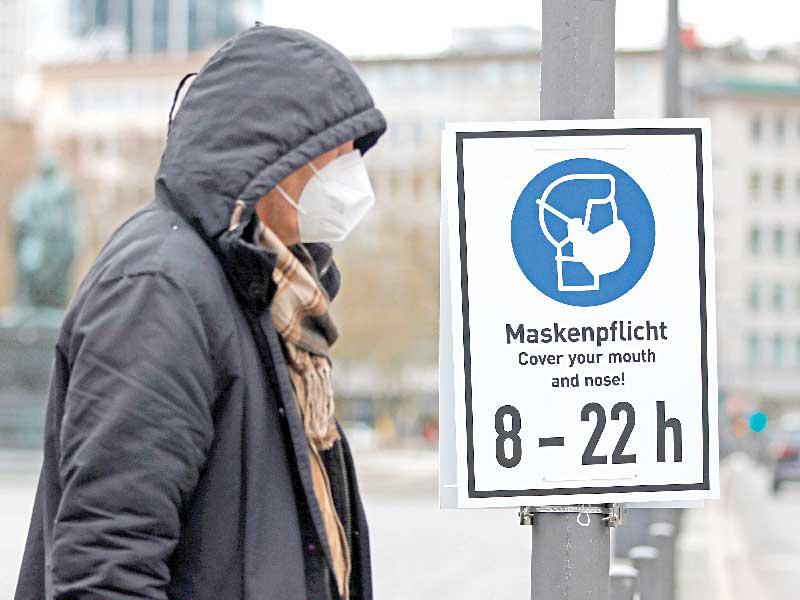 رجل يمرّ قرب لائحة تحذّر من عدم ارتداء الكمامة في فرانكفورت أمسt(اي بي ايه)