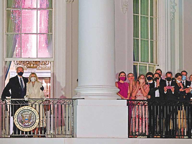 الرئيس الأميركي الجديد جو بايدن وعائلته يتابعون الألعاب النارية من شرفة الغرفة الزرقاء بالبيت الأبيض أمس الأول (أ ف ب)