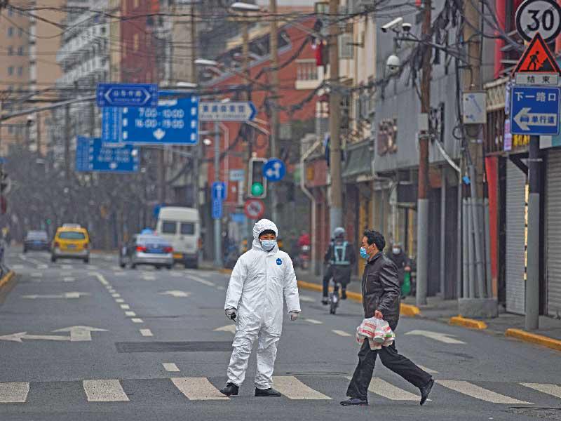 رجل يمرّ بشارع مغلق ضمن إجراءات العزل بسبب تفشي «كورونا» في شنغهاي أمس (اي بي ايه)