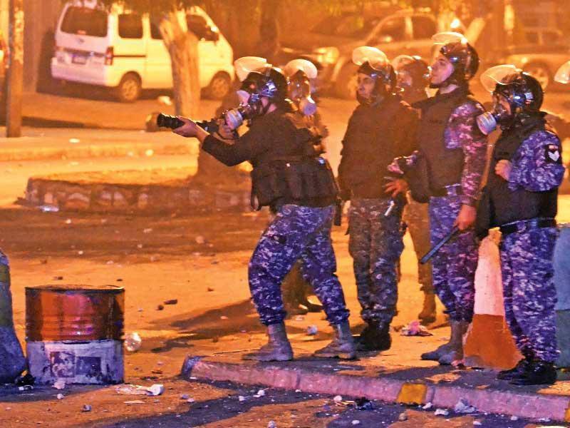 قوة أمنية خلال مواجهة متظاهرين في طرابلس مساء أمس الأول t(أ ف ب)