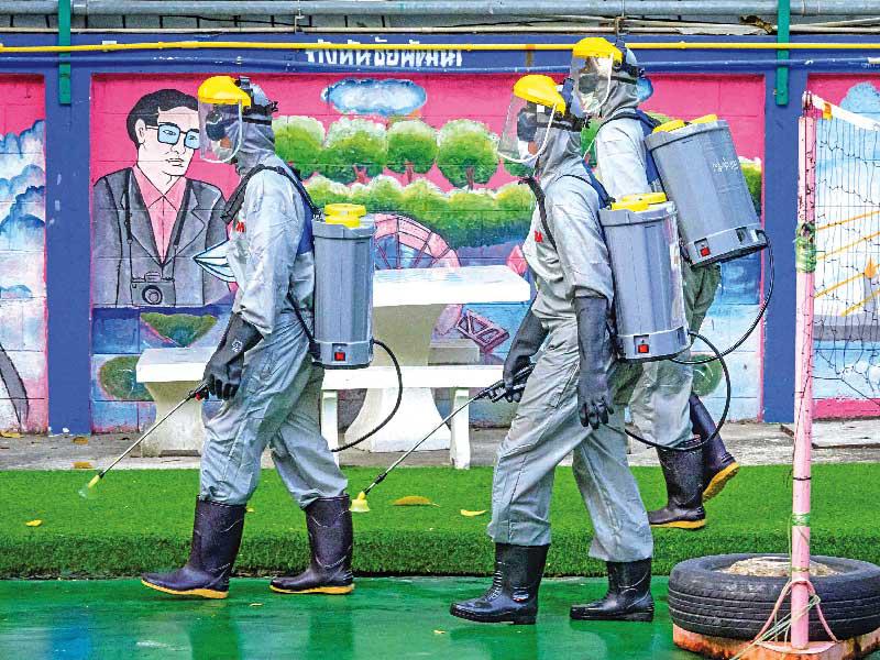 جنود تايلنديون يشاركون في تعقيم أحد الشوارع في بانكوك أمس  (ا ف ب)