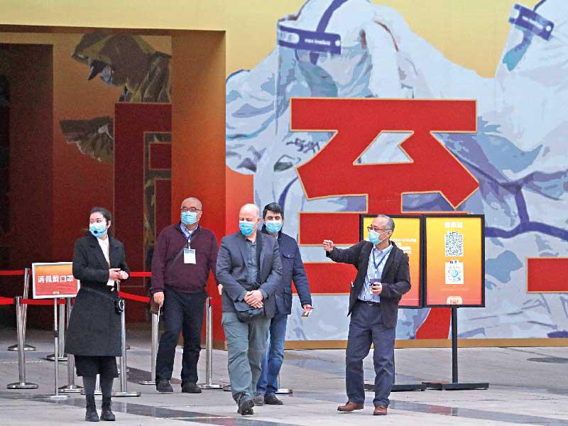 أعضاء من فريق «الصحة العالمية» يغادرون متحفاً دعائياً يحتفى بتعافي الصين من «كورونا» في ووهان أمس (رويترز)