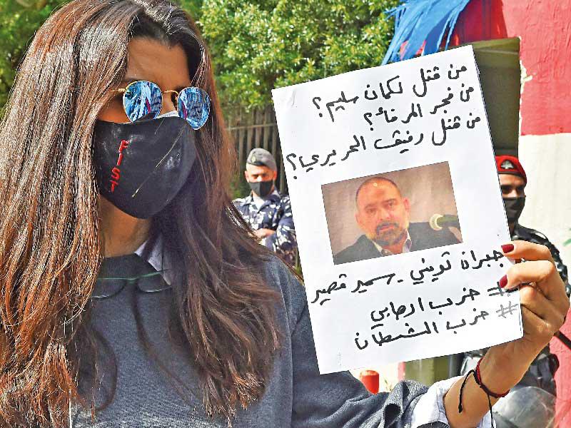 لبنانية تحمل يافطة عليها صورة لسليم وعبارات تتهم «حزب الله» باغتياله في وقفة أمام قصر العدل ببيروت أمس (أ ف ب)