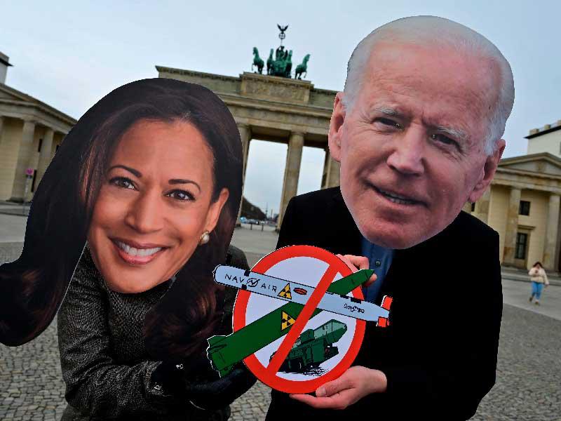 ناشطان يرتديان قناعين لبايدن ونائبته خلال احتجاج في برلين مؤيد لتفليص الأسلحة النووية في العالم (أ ف ب) 