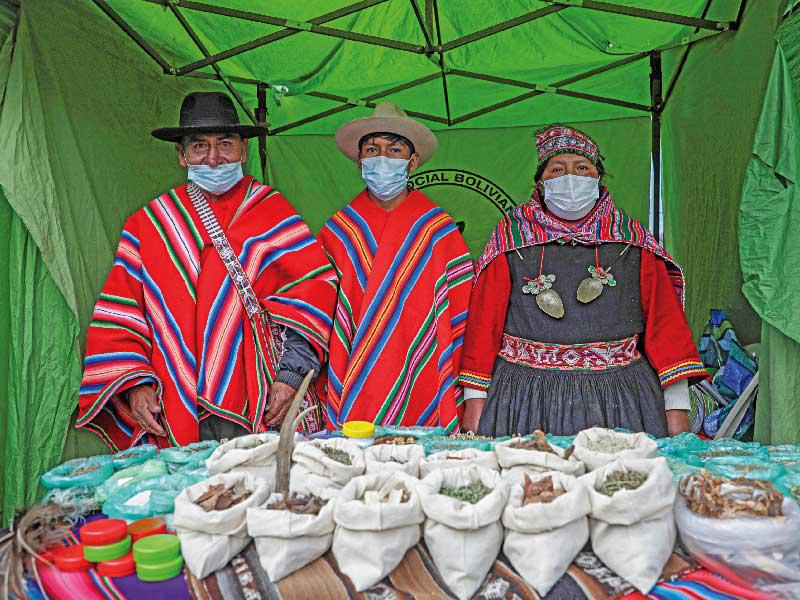 عائلة بوليفية تضع الكمامات في متجرها المخصّص لبيع الأعشاب المضادة لـ«كورونا» في مدينة لاباز (رويترز)