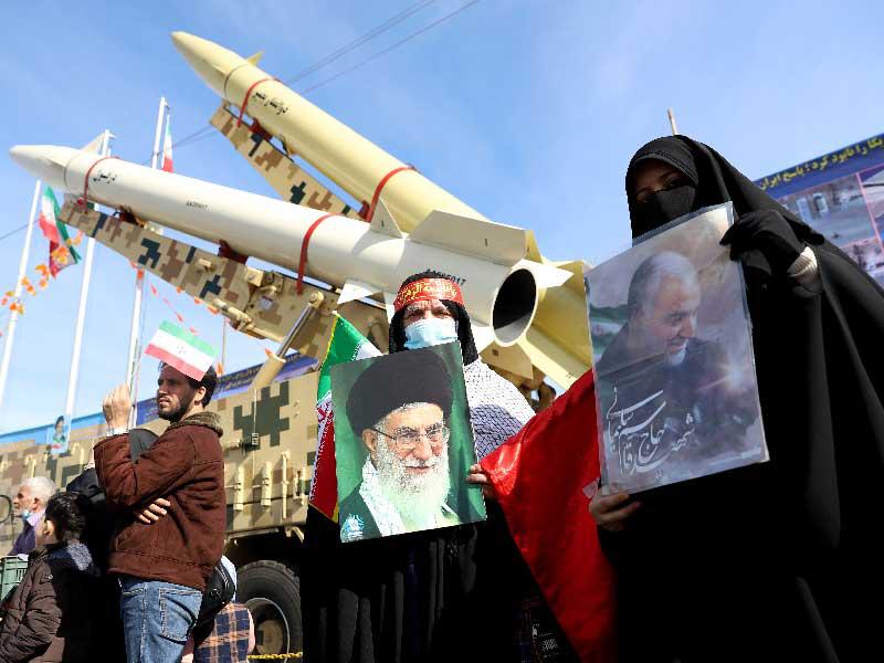 إيرانيون بجوار صواريخ باليستية عرضها «الحرس الثوري» احتفالاً بذكرى الثورة في طهران أمس     (رويترز)