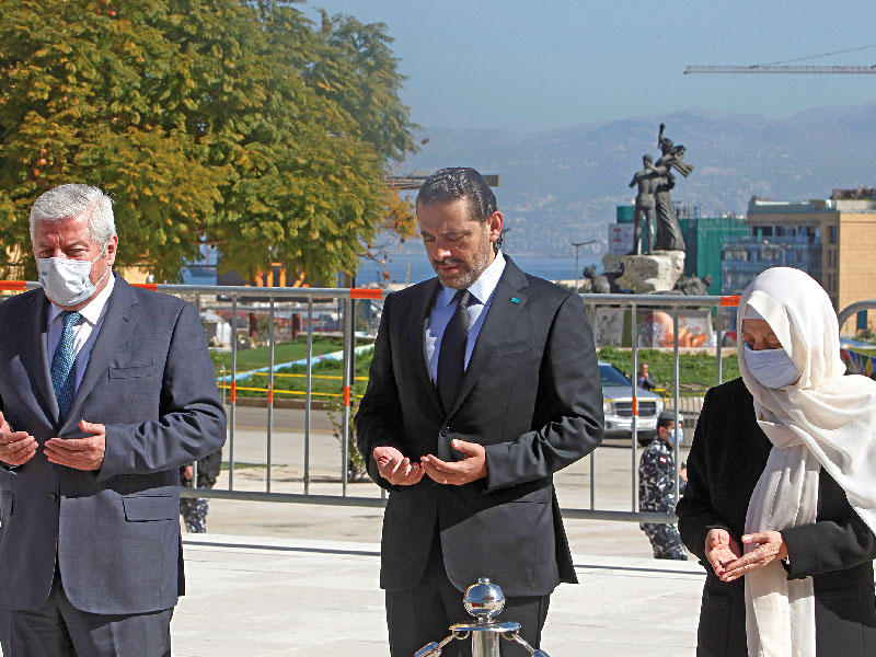 رئيس الحكومة اللبنانية المكلف سعد الحريري (في الوسط) يقرأ الفاتحة على ضريح والده وسط بيروت أمس (رويترز)