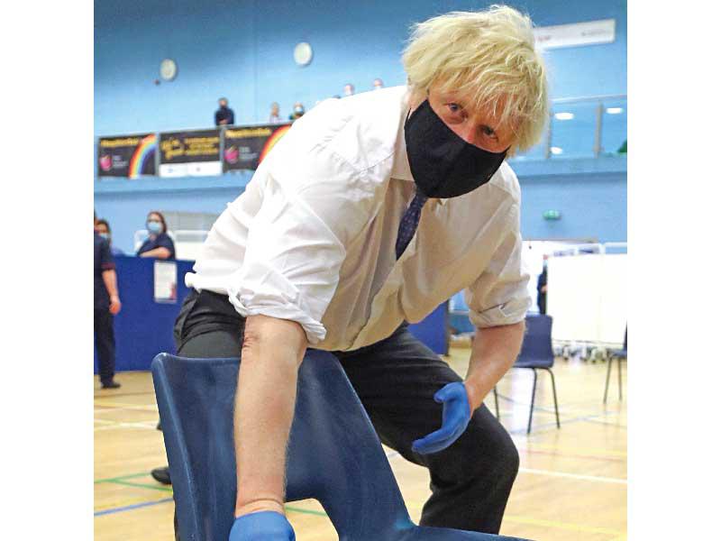 رئيس وزراء بريطانيا يعقم كرسياً أثناء زيارته لمركز تطعيم في ملعب كومبران جنوب ويلز أمس    (رويترز)