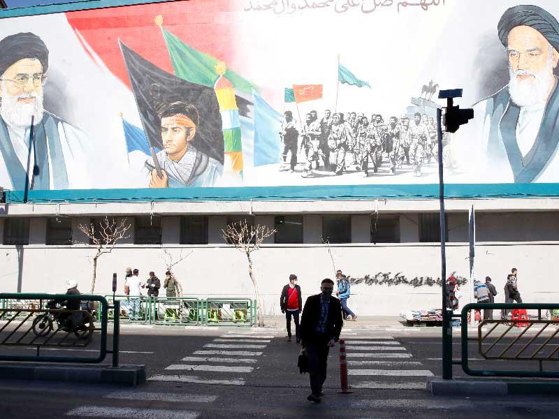 إيرانيون يمرون أمام جدارية لخامنئي وخميني في طهران  (أي بي أيه) 