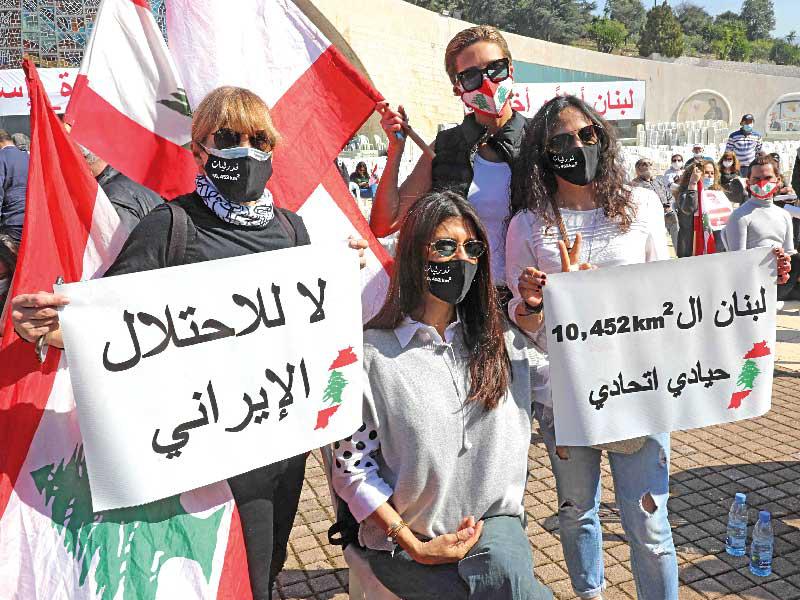 لبنانيات يرفعن لافتات مندّدة بـ«الاحتلال الإيراني» في باحة البطريركية المارونية في بكركي أمس الأول (أ ف ب)