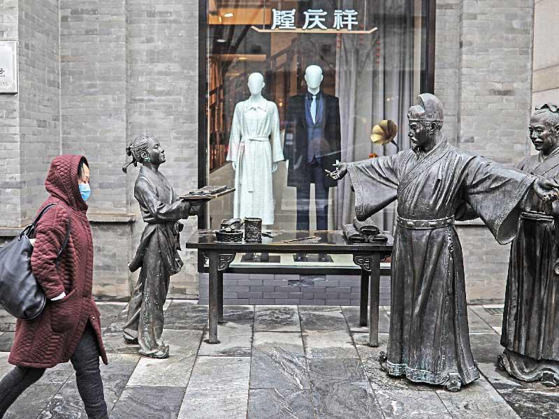 صينيون يمرون في شارع كيانمين التجاري ببكين أمس (اي بي أيه)