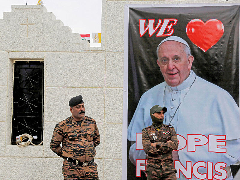 جنديان قرب صورة كبيرة للبابا في بغداد أمس (رويترز)