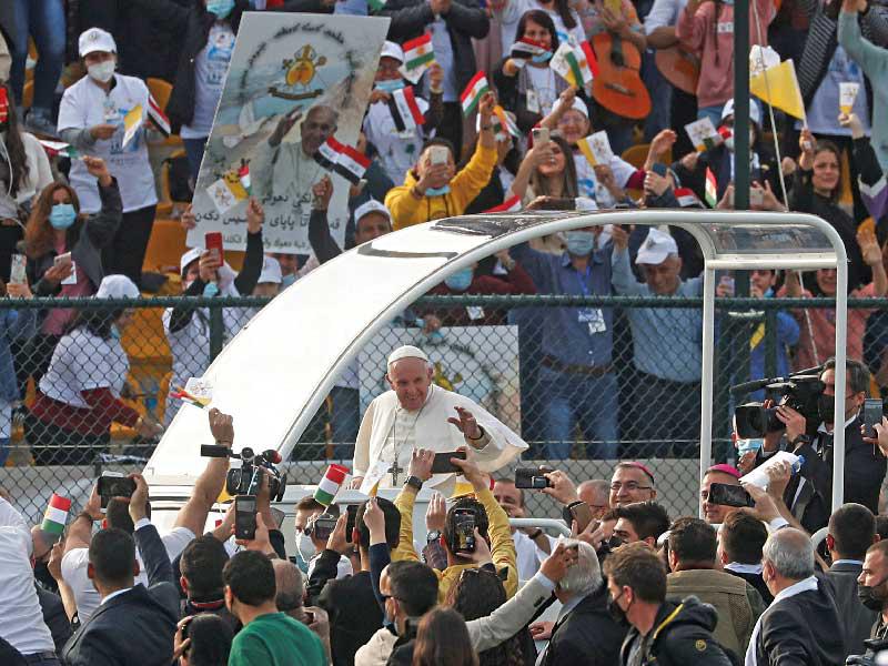 البابا يحيي مستقبليه في ملعب فرانسوا الحريري بأربيل أمس (رويترز)