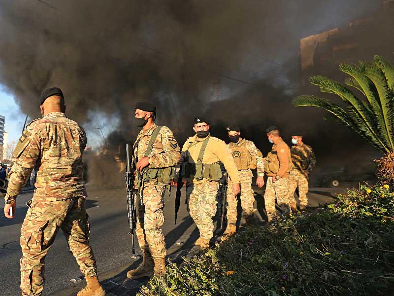 جنود يتفادون غبار الإطارات المحروقة في صيدا أمس الأول (رويترز)n