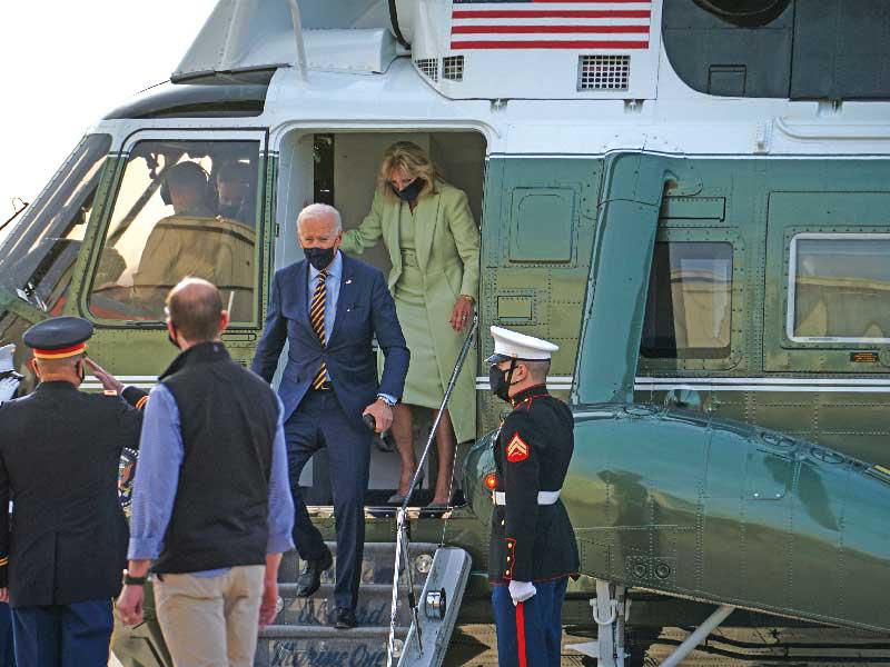 جو بايدن وزوجته لحظة وصولهما بالمروحية إلى قاعدة عسكرية في نيوكاسل (رويترز)