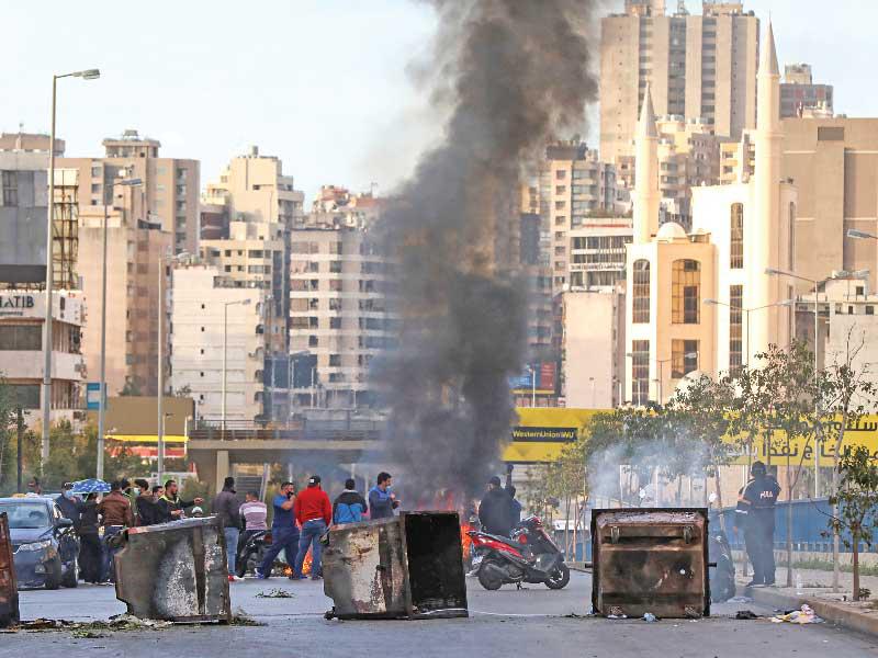 لبنانيون يغلقون طريقاً بحاويات النفايات خلال تظاهرة في بيروت           (رويترز)