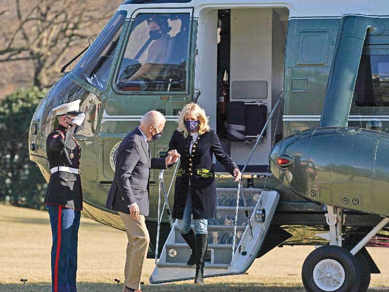 الرئيس الأميركي جو بايدن يساعد زوجته جيل لدى عودتهما من كامب ديفيد أمس الأول (رويترز)