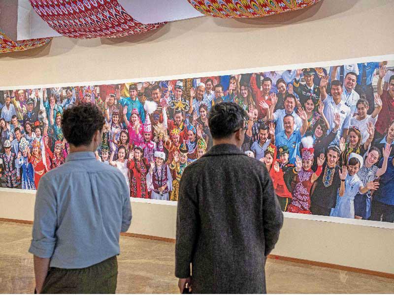 صينيان في معرض ببكين أمس يقفان أمام صورة كبيرة التقطت في إقليم شينجيانغt(أ ف ب)