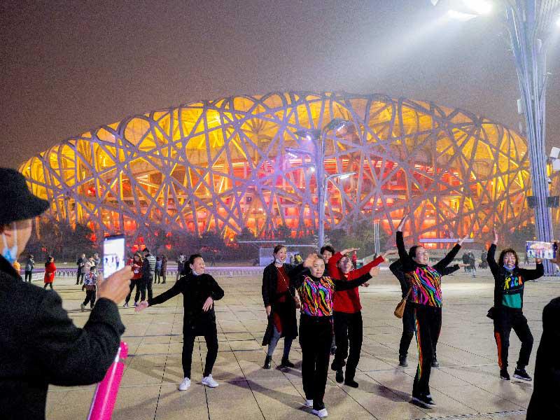 صينيون أمام الاستاد الوطني في بكين، المعروف بـ «عش العصافير»، قبل إطفاء أنواره بمناسبة يوم الأرض أمس (رويترز)