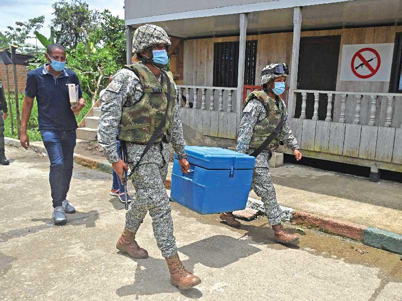 جنديان يوزعان لقاح كورونا الصيني في منطقة نائية من كولومبيا أمس (أ ف ب)