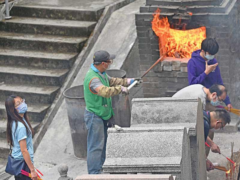 صينيون يقدمون تحية نارية لموتاهم بمهرجان تشينغ مينغ في مقبرة كيب كولينسون أمس (أ ف ب)