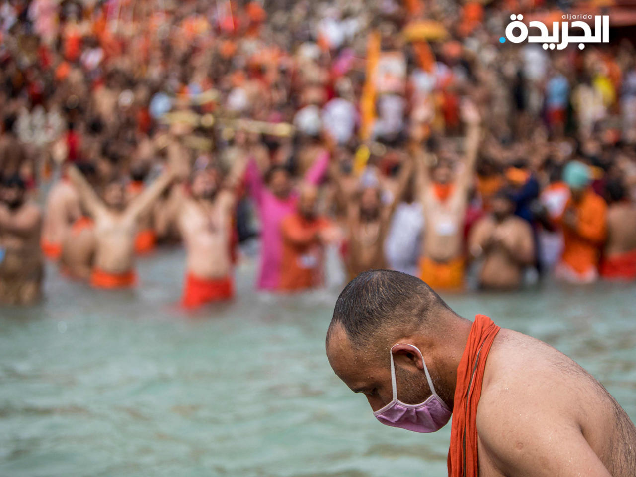 راهب يرتدي قناعاً للوجه ويغطس في نهر الغانج خلال مهرجان كومبه