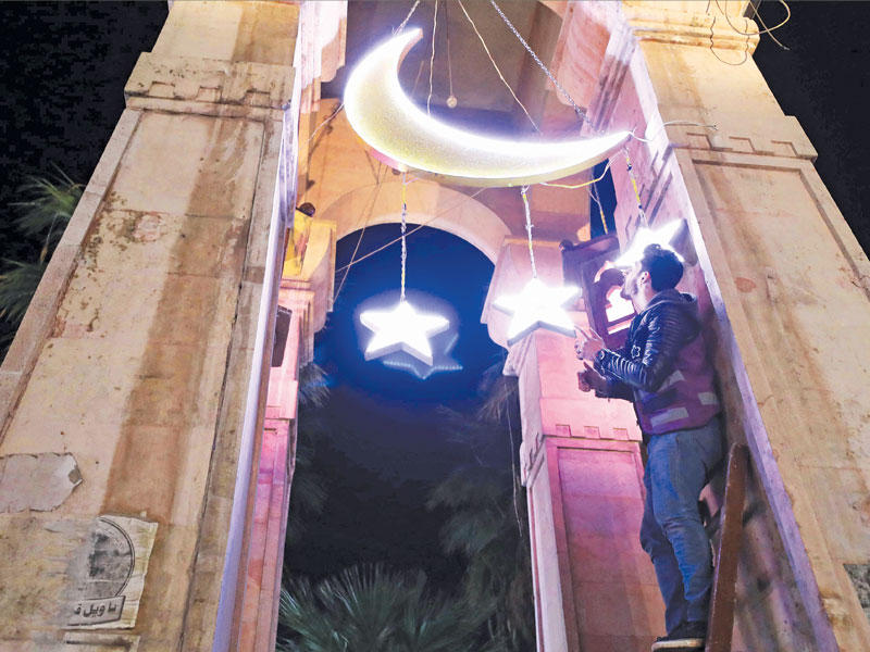 سوري يضع زينة رمضانية في إدلب     (أ ف ب)