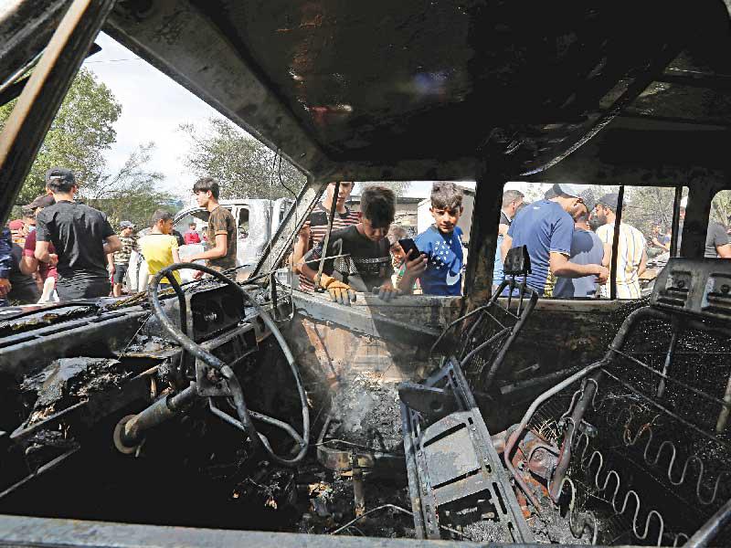 أطفال عراقيون يتفقدون سيارة احترقت بعد الانفجار في مدينة الصدر أمس     (رويترز)