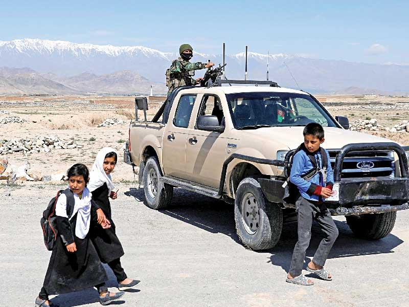 طلاب مدرسة يمرّون أمام نقطة عسكرية في كابول امس (رويترز)