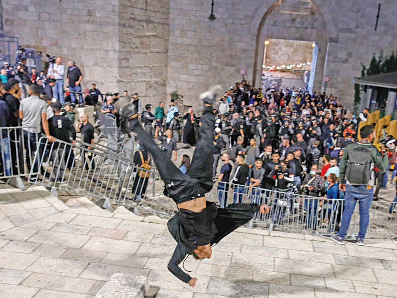 فلسطيني يقوم بحركة استعراضية قبل طرد القوات الإسرائيلية للمتظاهرين خارج باب العامود في البلدة القديمة بالقدس أمس الأول    (أ ف ب)