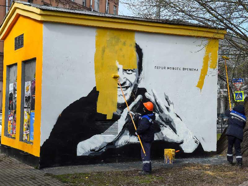 عامل يزيل جدارية لنافالني كتب عليها «بطل العصر الجديد» في سان بطرسبورغ أمس (أ ف ب)