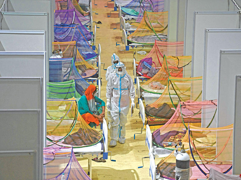 ممرضون بين أسرّة مرضى «كورونا» في مستشفى ميداني أقيم بأحد النوادي الرياضية في نيودلهي أمسt (أ ف ب)