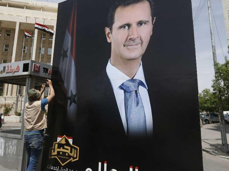 سوري يثبت صورة كبيرة للرئيس الحالي بشار الأسد في دمشق (أ ف ب)