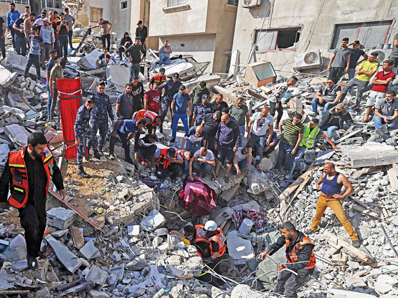 عمال إنقاذ يبحثون عن ناجين تحت أنقاض عمارة دمّرها القصف الإسرائيلي في حي الرمال بغزة أمس      (أ ف ب)