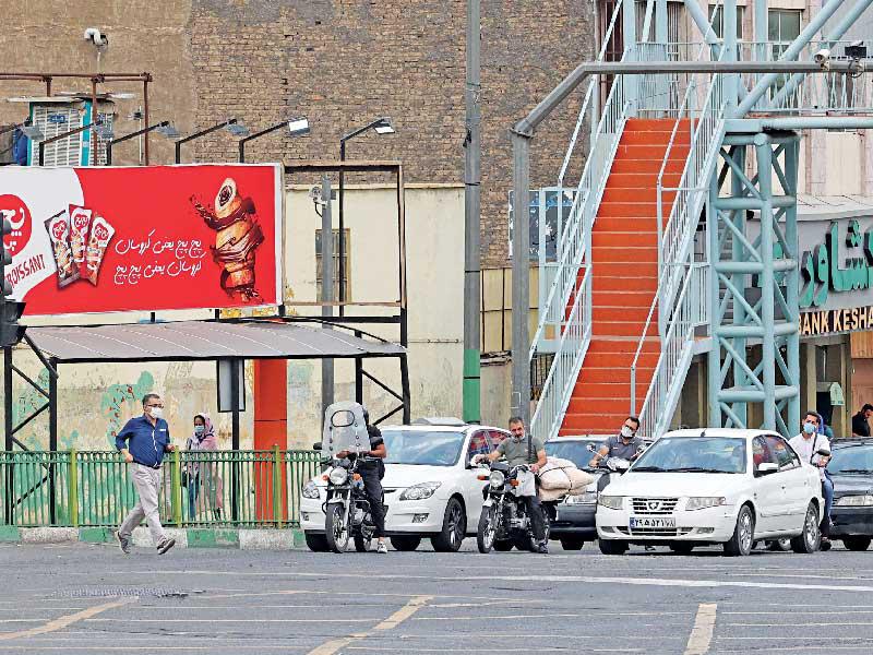 شرطي إيراني يحاول تنظيم السير بنفسه قبل أيام في طهران بعد انقطاع الكهرباء عن إشارات المرور   (أ ف ب) 