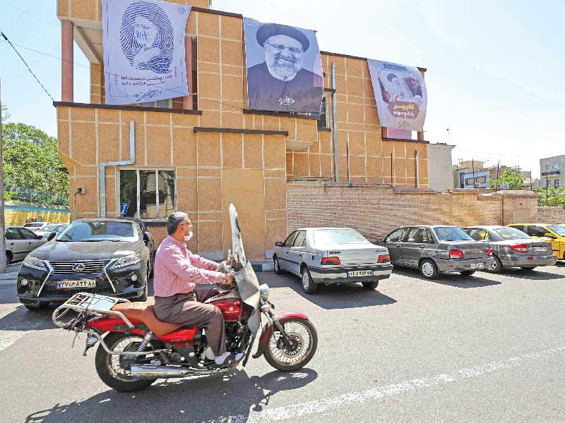 إيراني في طهران يمر أمام صورة لرئيسي، المرشح الوحيد الذي يملك فرصة للفوز في الانتخابات t(أ ف ب)