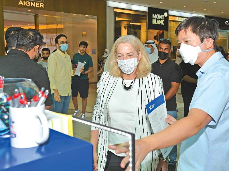 السفيرة الأميركية لدى الكويت الينا رومانوسكي تستمع لشرح عن أحد البوثات في المعرض